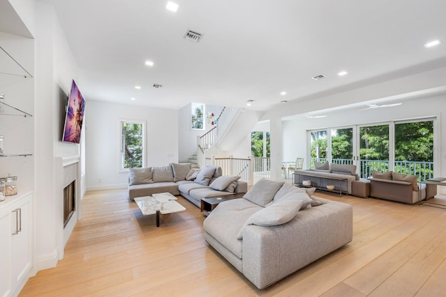 living room with ceiling fan, plenty of natural light, and light wood-type flooring