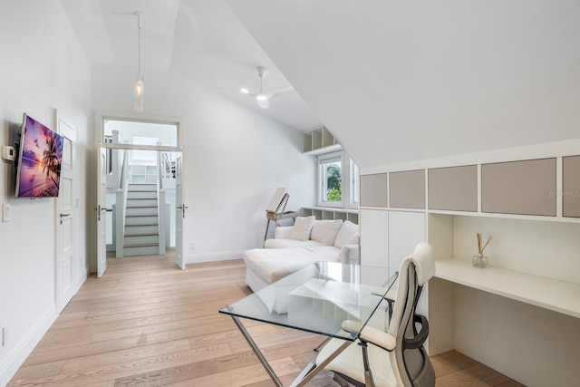 office space with built in desk, light wood-type flooring, and vaulted ceiling