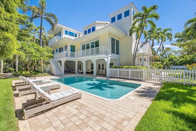 rear view of house with a patio, a balcony, and a fenced in pool