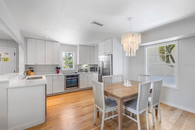 dining area with a notable chandelier, light wood-type flooring, and sink