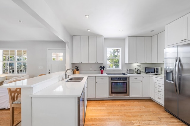 kitchen with kitchen peninsula, white cabinetry, sink, and stainless steel appliances