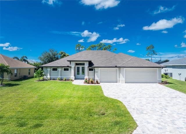 view of front of home with a garage, a front yard, and central AC