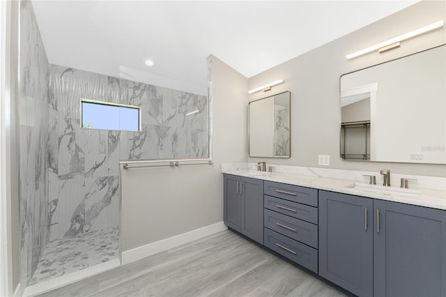 bathroom featuring wood-type flooring, vanity, and a tile shower