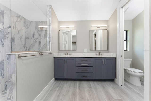 bathroom featuring hardwood / wood-style flooring, vanity, toilet, and a tile shower