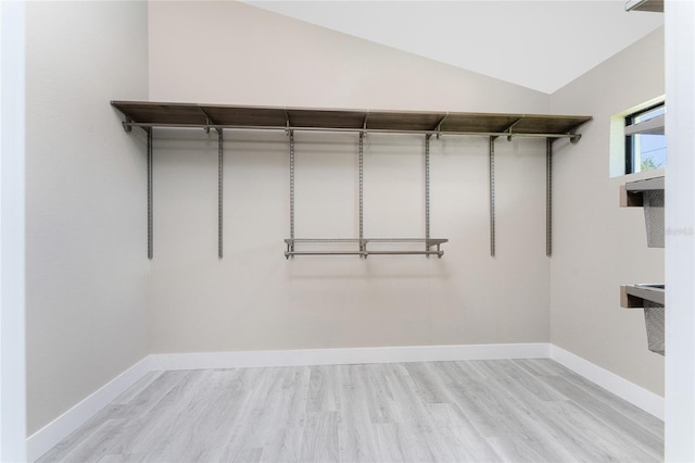 spacious closet with light hardwood / wood-style floors and lofted ceiling