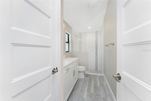 bathroom featuring hardwood / wood-style flooring, toilet, a shower, and vanity