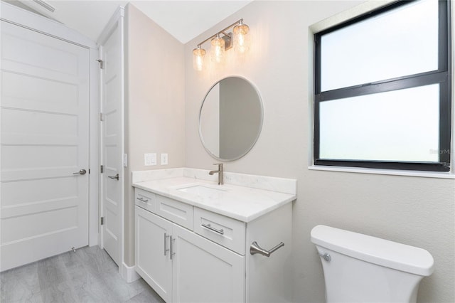 bathroom with toilet, vanity, vaulted ceiling, and hardwood / wood-style flooring