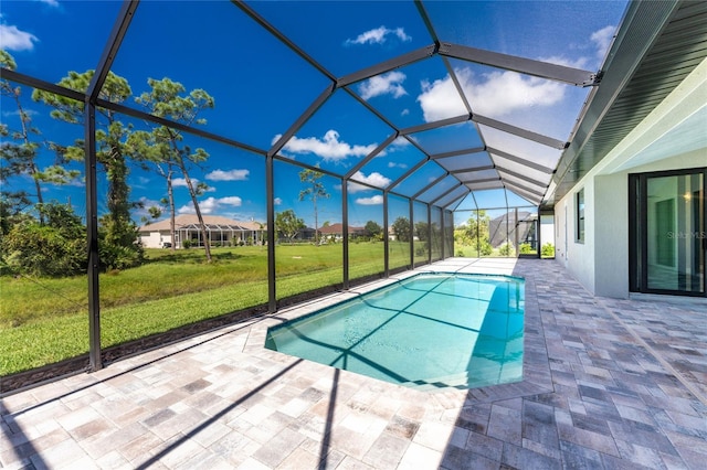 view of pool with a lawn, glass enclosure, and a patio area