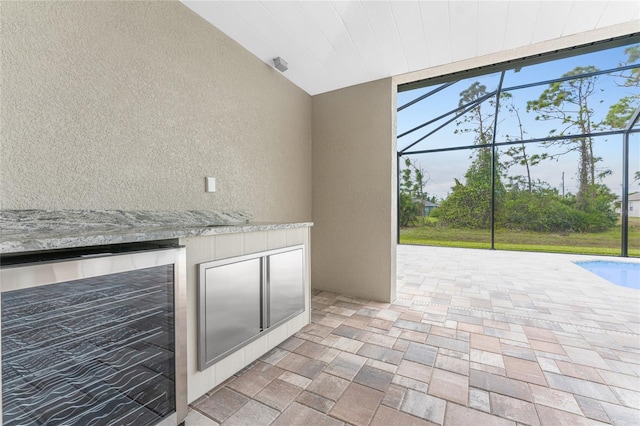 view of patio with a lanai, beverage cooler, and exterior kitchen