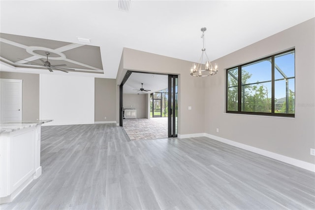 unfurnished living room featuring ceiling fan with notable chandelier, light hardwood / wood-style flooring, and plenty of natural light