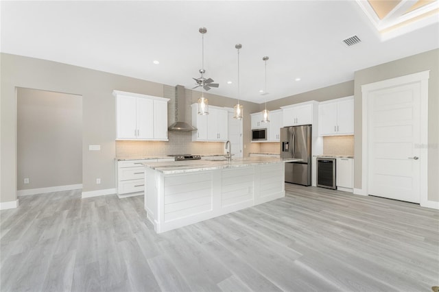 kitchen with white cabinets, wall chimney exhaust hood, beverage cooler, and appliances with stainless steel finishes