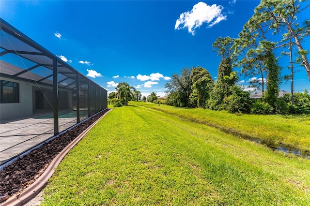 view of yard featuring glass enclosure and a patio area