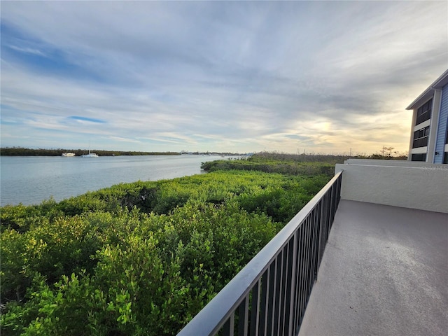 balcony at dusk featuring a water view