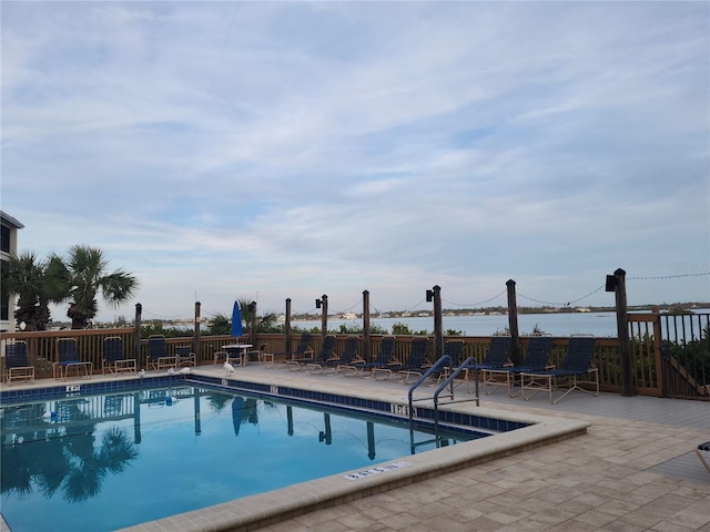 view of swimming pool featuring a water view and a patio