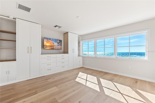 unfurnished bedroom with two closets, light wood-style flooring, visible vents, and baseboards