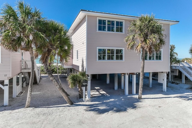 coastal inspired home featuring stairs, a carport, and driveway