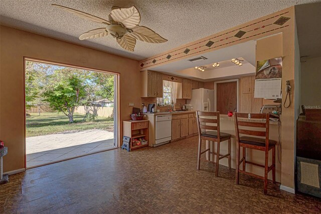 kitchen with a textured ceiling, white appliances, and ceiling fan