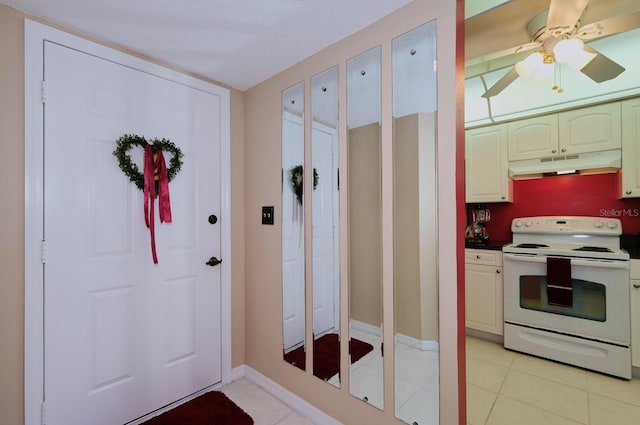 kitchen with white range with electric cooktop, ceiling fan, light tile patterned floors, and a textured ceiling