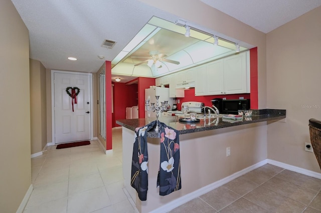 kitchen featuring white cabinets, white refrigerator, kitchen peninsula, stainless steel stove, and washer and dryer