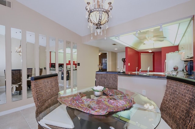 tiled dining area featuring ceiling fan with notable chandelier, vaulted ceiling, and sink