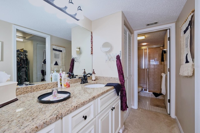 bathroom with vanity, toilet, an enclosed shower, and a textured ceiling