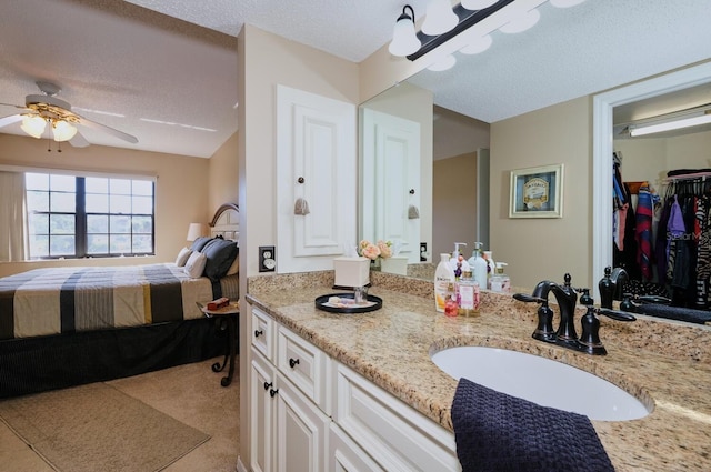 bathroom featuring ceiling fan, vanity, and a textured ceiling