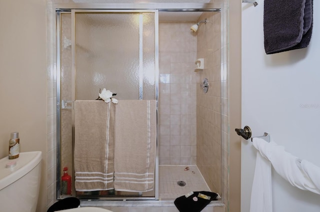 bathroom featuring toilet and a shower with door