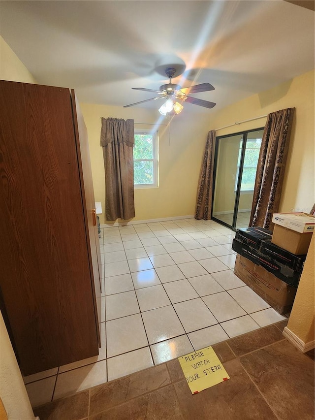 unfurnished living room featuring a wealth of natural light, light tile patterned floors, and ceiling fan