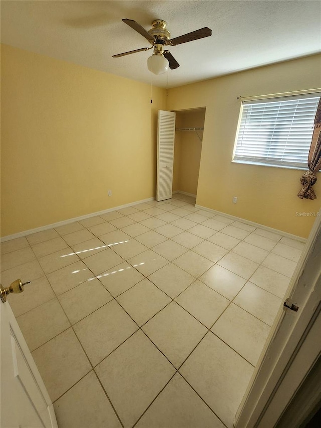 unfurnished bedroom with ceiling fan, light tile patterned flooring, and a closet