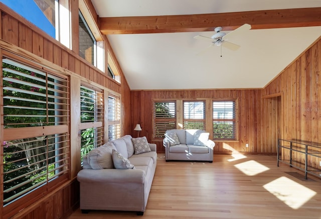 living room featuring beam ceiling, ceiling fan, light hardwood / wood-style flooring, and wood walls