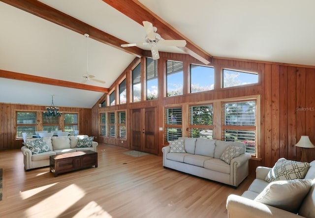 living room featuring wood walls, beam ceiling, light wood-type flooring, and high vaulted ceiling