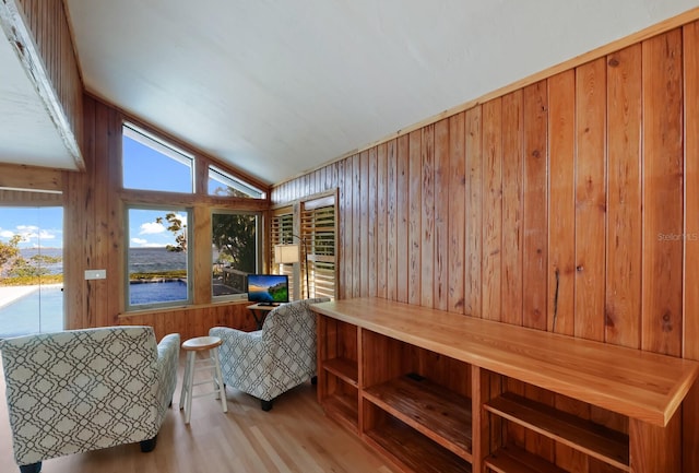 sitting room featuring wooden walls, light hardwood / wood-style floors, and vaulted ceiling