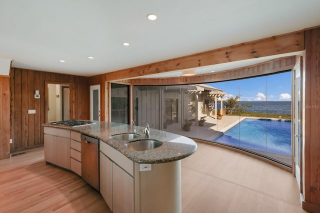 kitchen with wood walls, white cabinets, sink, appliances with stainless steel finishes, and stone countertops