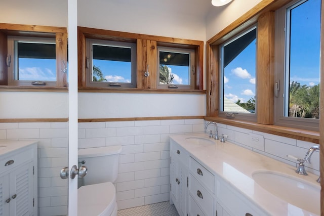 bathroom featuring tile patterned flooring, vanity, toilet, and tile walls