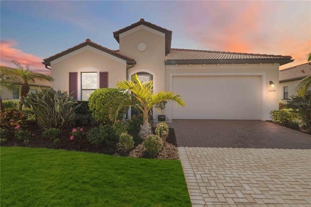 mediterranean / spanish-style house featuring a garage and a lawn