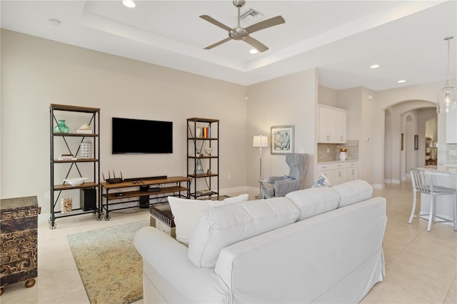 tiled living room featuring a tray ceiling and ceiling fan