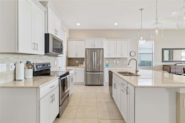 kitchen with white cabinetry, a kitchen island with sink, hanging light fixtures, sink, and appliances with stainless steel finishes