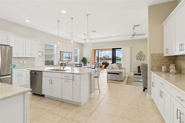 kitchen featuring white cabinetry, an island with sink, stainless steel appliances, sink, and pendant lighting