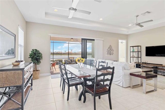 dining room featuring a raised ceiling, light tile patterned floors, and ceiling fan