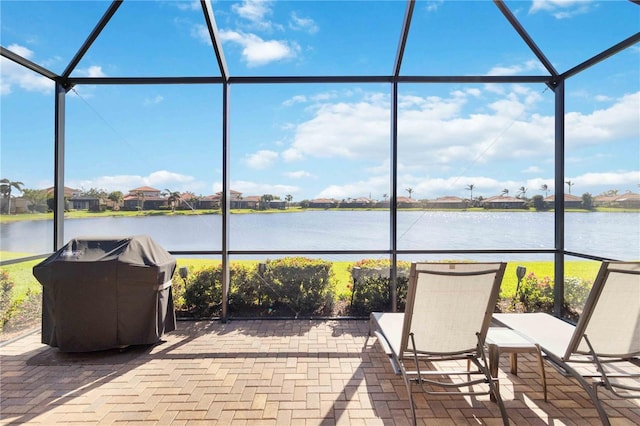 view of patio with a water view, a lanai, and a grill