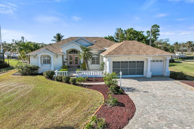 view of front facade with a garage, a front lawn, and french doors