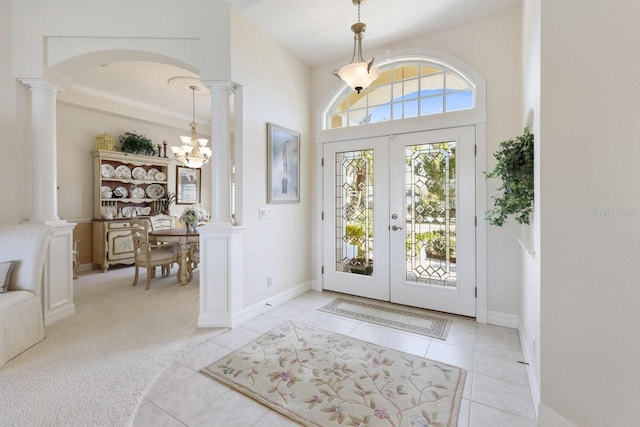 carpeted foyer with decorative columns, an inviting chandelier, and french doors