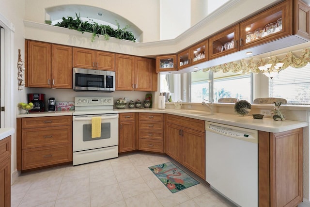 kitchen featuring white appliances, a towering ceiling, sink, and light tile patterned floors