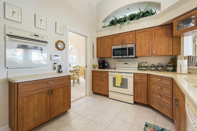 kitchen with sink, light tile patterned floors, and white appliances