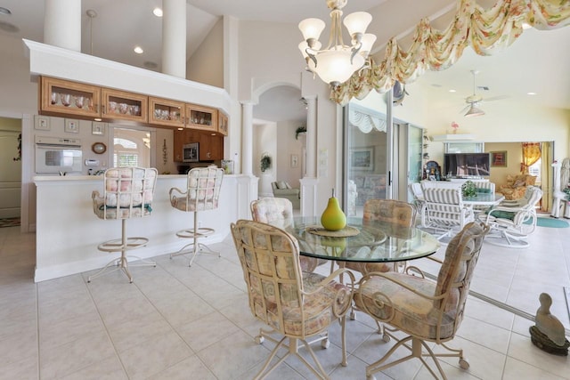 dining area featuring ornate columns, a chandelier, high vaulted ceiling, and light tile patterned floors