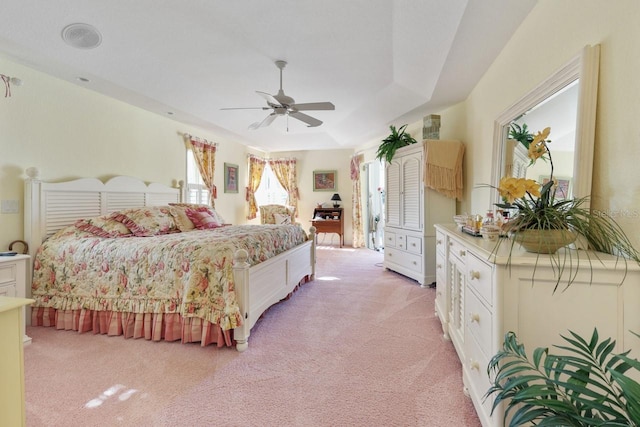 carpeted bedroom featuring ceiling fan and a tray ceiling