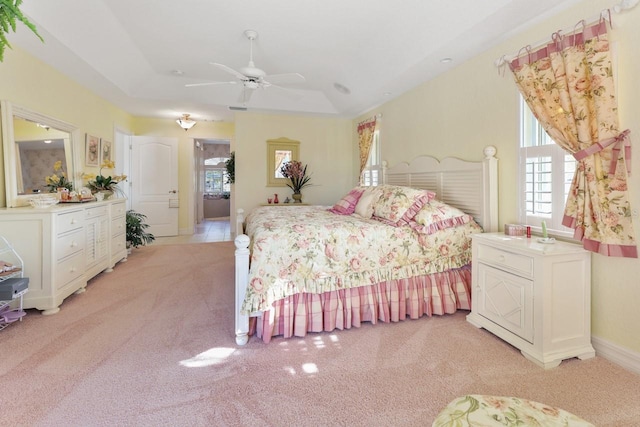 carpeted bedroom with a raised ceiling and ceiling fan