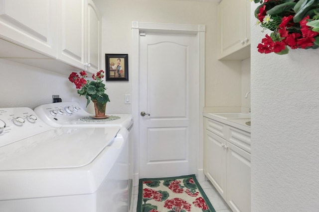 clothes washing area featuring cabinets, washing machine and clothes dryer, sink, and light tile patterned floors