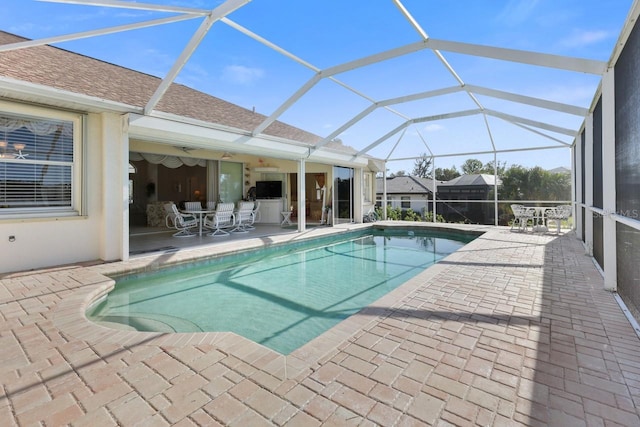 view of pool with a patio, ceiling fan, and glass enclosure