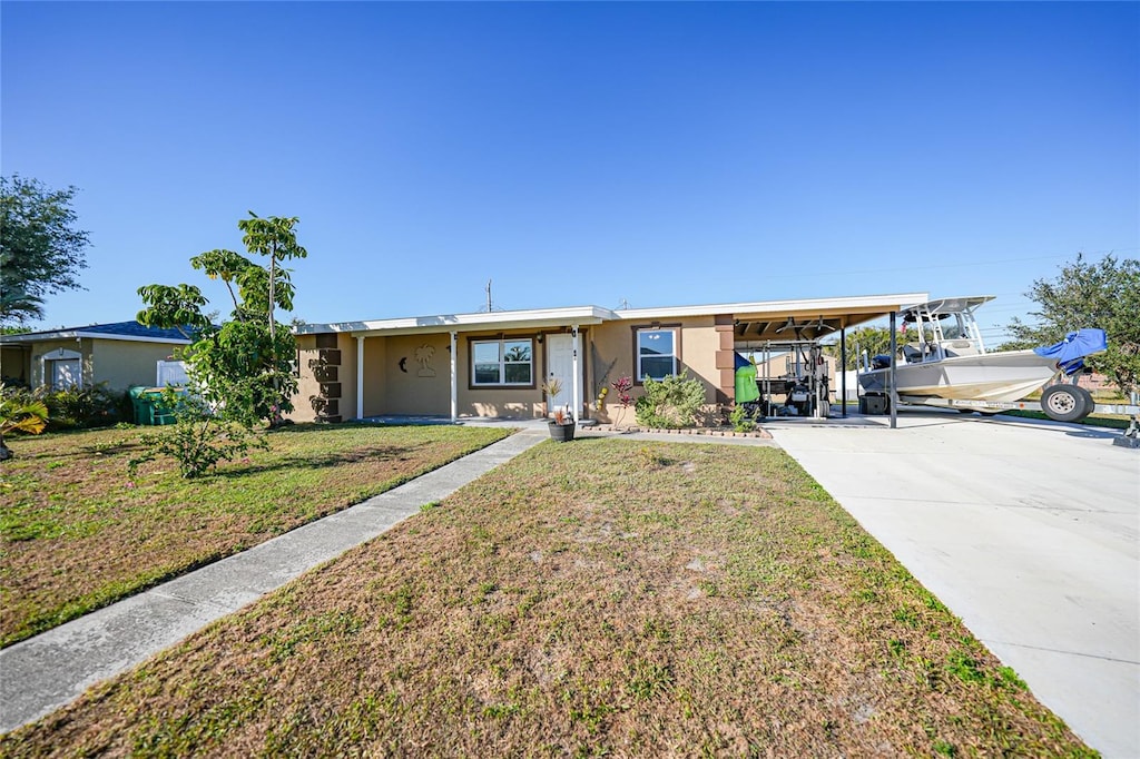 ranch-style home featuring a front lawn and a carport